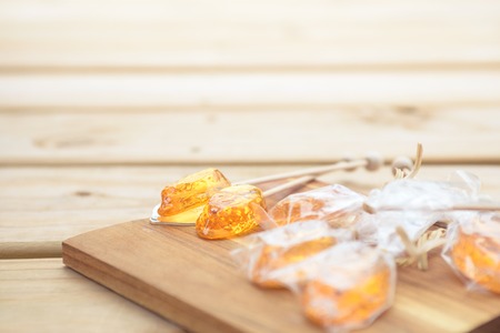 Honey caramel candy lollipop on wooden backgroundの写真素材