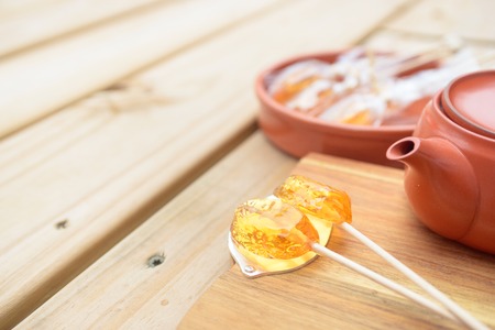 Candy lollipop and teapot on wooden backgroundの写真素材