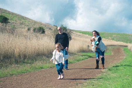 Happy family of four hiking in the park with beautiful viewの写真素材