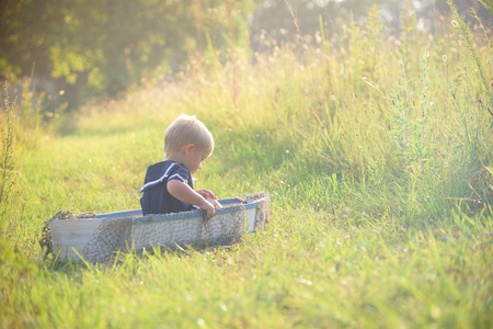 Boy in vintage sailor suit in boat on grassの写真素材