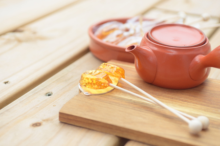 Candy lollipop and teapot on wooden backgroundの写真素材
