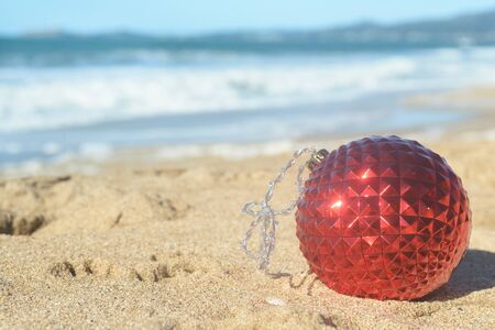 Red Christmas ball in the sand on the beachの写真素材