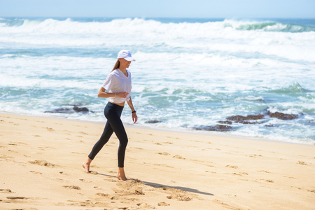 Smiling active young woman doing sports excercises on the beachの写真素材