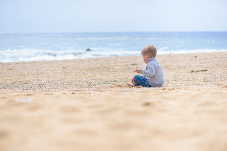 Happy boy playing in sand on the beach on vacationの写真素材
