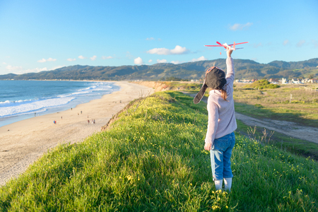 Girl in aviator hat playing pilot with toy plane outsideの写真素材