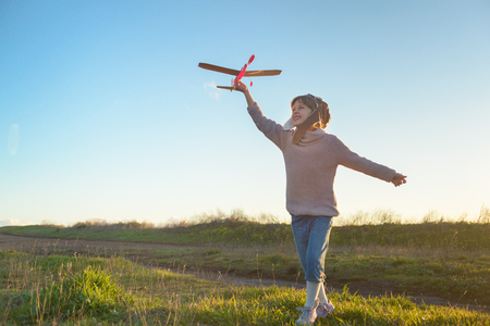 Girl in aviator hat playing pilot with toy plane outsideの写真素材