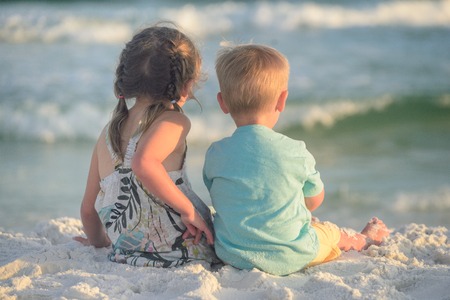 Boy and girl playing on the beach at sunsetの写真素材
