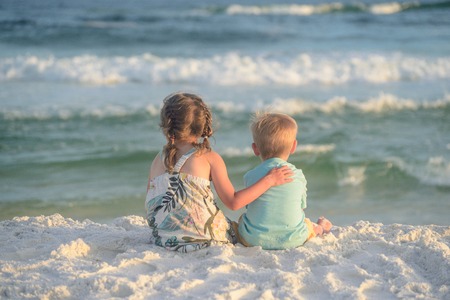 Boy and girl playing on the beach at sunsetの写真素材