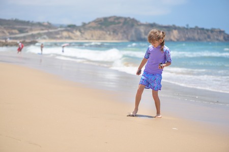 Happy girl playing on the beach near the oceanの写真素材