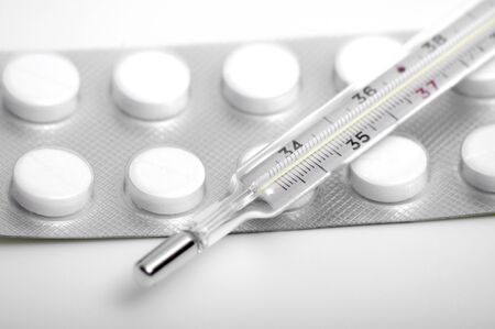 Close-up medical thermometer and pills