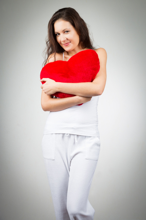 Woman holding heart-shaped pillowの写真素材