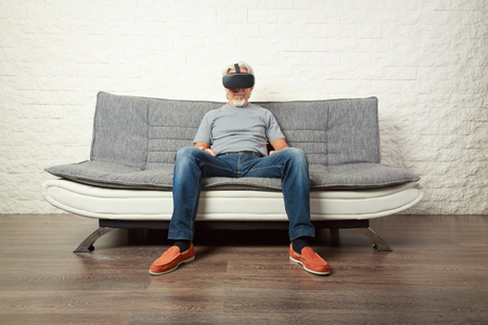 Senior Man Wearing Vr Glasses, Sitting On Couchの写真素材