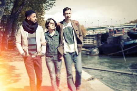 Multi-ethnic group of friends having fun in Paris along the Seine river, near Eiffel Tower.