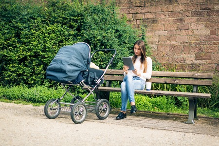 Young Mother With Baby Stroller In The Parkの写真素材