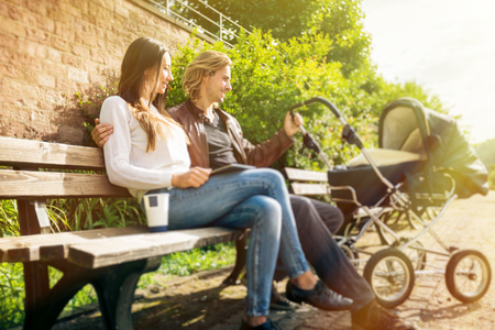 Young Parents With Baby Stroller In The Parkの写真素材