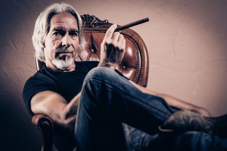 Senior Man Sitting In Armchair, Studio Portraitの写真素材