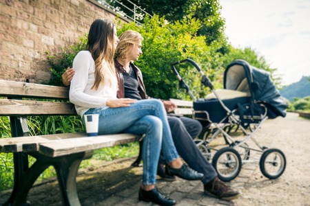 Young Parents With Baby Stroller In The Parkの写真素材
