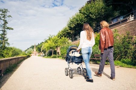 Young Parents With Baby Stroller In The Parkの写真素材