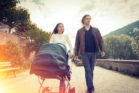 Young Parents With Baby Stroller In The Park