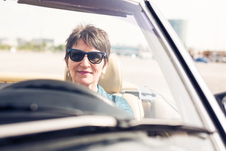 Senior Woman Driving A Convertible Classic Carの写真素材