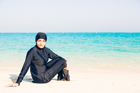 Young Woman Wearing Burkini Sitting By The Beachの写真素材