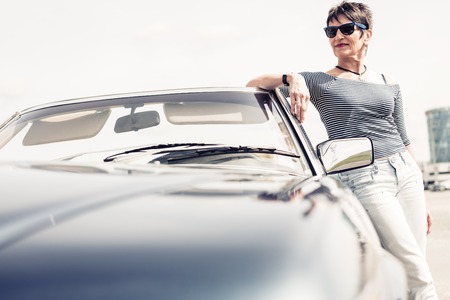 Senior Woman Standing Next To Convertible Classic Car