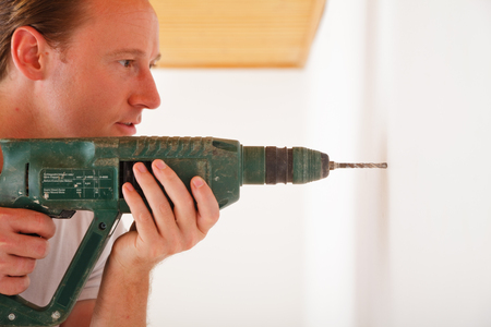 Young Man Drilling A Hole Into The Wallの写真素材