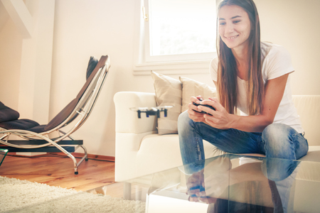 Young Woman Playing With A Small Quadrocopter Droneの写真素材