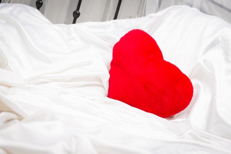 Heart-shaped Pillow On White Sheetsの写真素材