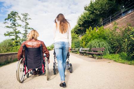Young Parents In Wheelchair With Baby Stroller In The Parkの写真素材