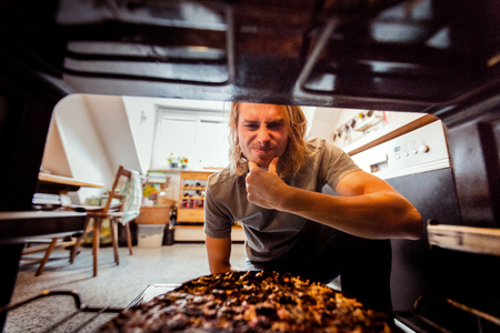 Man Taking Burnt Pizza From Stoveの写真素材