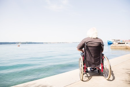 happy old man in wheelchair looking at the seaの写真素材