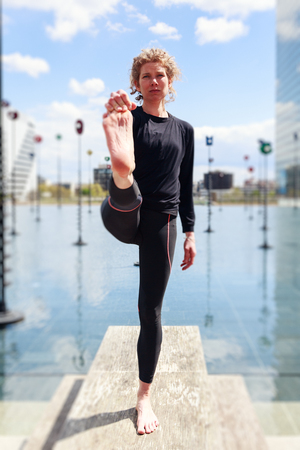 Woman Doing Yoga Near Lake In Urban Setting, Parisの写真素材