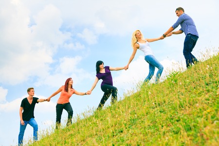 Young People Helping Each Other Climb A Hillの写真素材