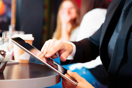 Businessman Sitting In A Cafe, Working On His Tabletの写真素材
