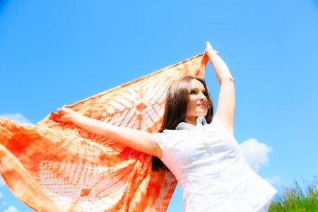 woman on green meadow, holding colorful scarfの写真素材