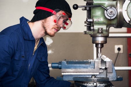 young mechanic apprentice working on milling machine