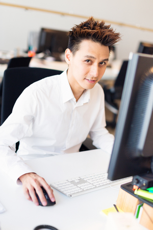 Young Asian Office Worker At His Deskの写真素材