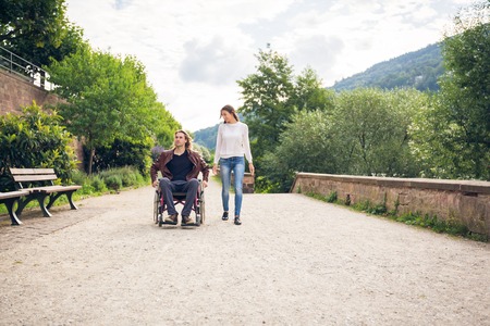 Young Couple In Wheelchair Strolling In The Parkの写真素材