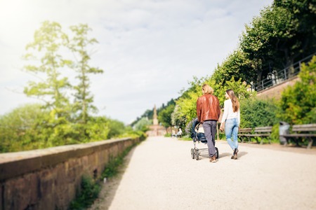 Young Parents With Baby Stroller In The Park