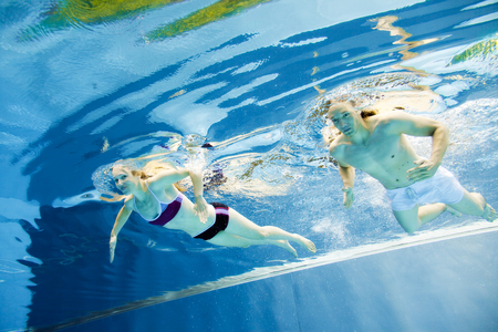 Underwater View Of A Young Couple Swimming In The Poolの写真素材
