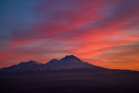 Snowy Mount Hasan. Volcano in Aksaray Turkey, Anatolia. Sunset. Pink Red Orange skyの写真素材