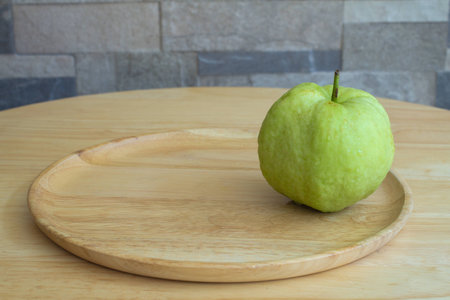 Guava in tray put on wood table blur wall backgroundの写真素材