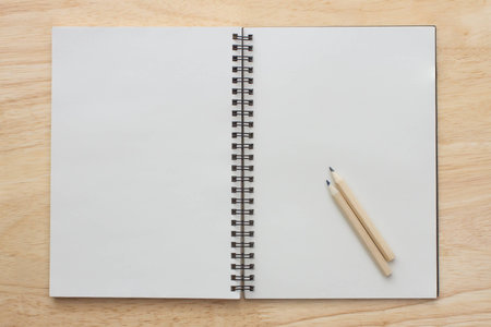 Open notebook and two wood pencils on notebook wooden background
