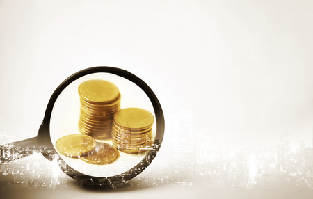 Double exposure of city and the magnifying glass focus at rows of coins for finance and banking conceptの写真素材