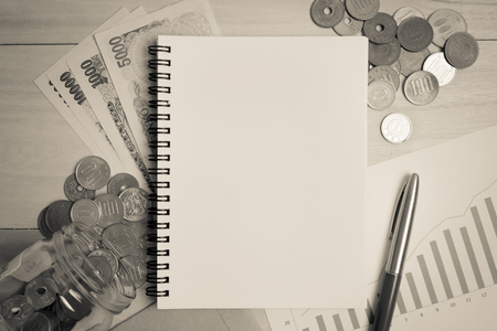 blank space note book , yen notes and asian coins for money concept backgroundの写真素材