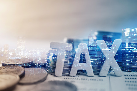 Double exposure of city, "tax" wooden text and rows of coins for finance and banking conceptの写真素材