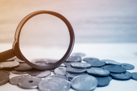 the magnifying glass focus on coins for finance and banking conceptの写真素材