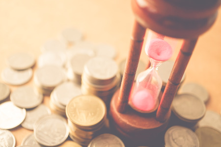 coin money and hourglass for about time of finance conceptの写真素材