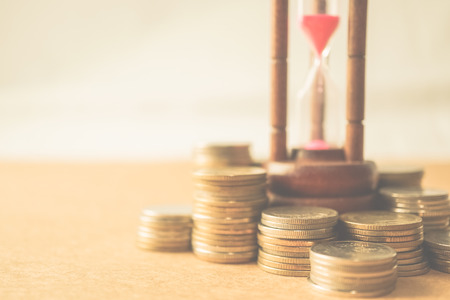 coin money and hourglass for about time of finance concept